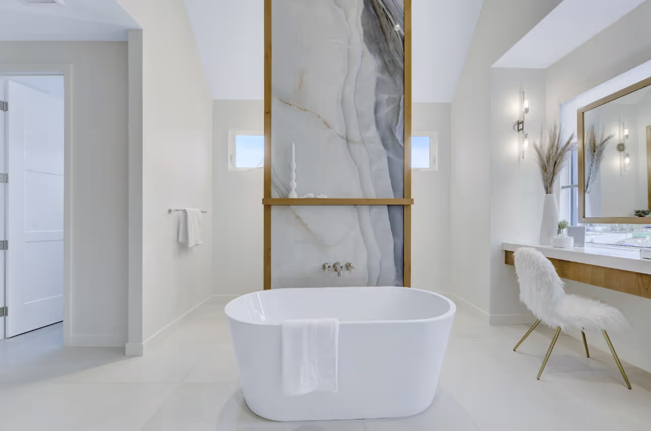 Luxury bathroom with freestanding soaker tub, marble feature wall, and custom double vanity cabinetry. Cabinetry by Marvel Cabinetry.