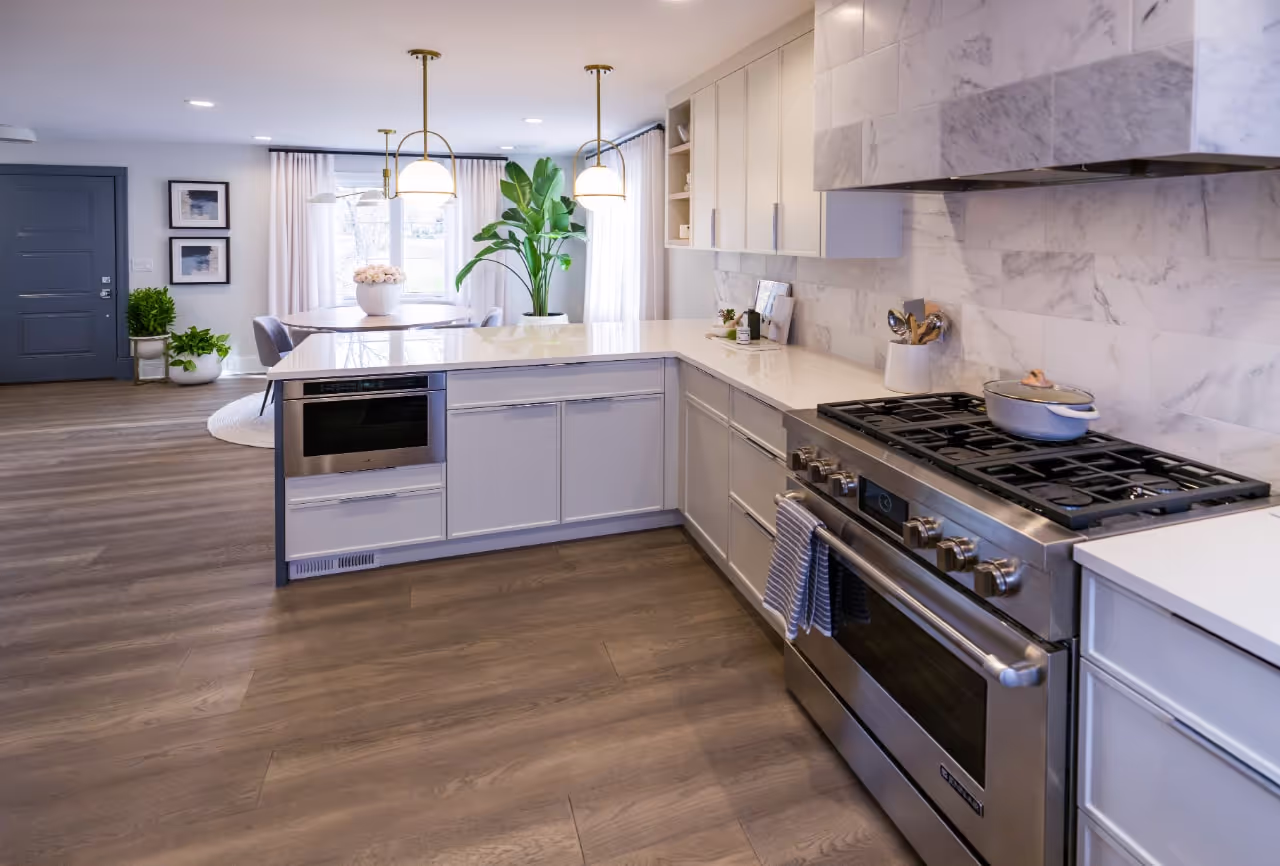 Bright modern kitchen featuring custom white cabinetry, marble backsplash, large island, and professional appliances from Viola Davis’ Celebrity IOU renovation. Cabinetry by Marvel Cabinetry for HGTV’s Property Brothers: Celebrity IOU - Viola Davis