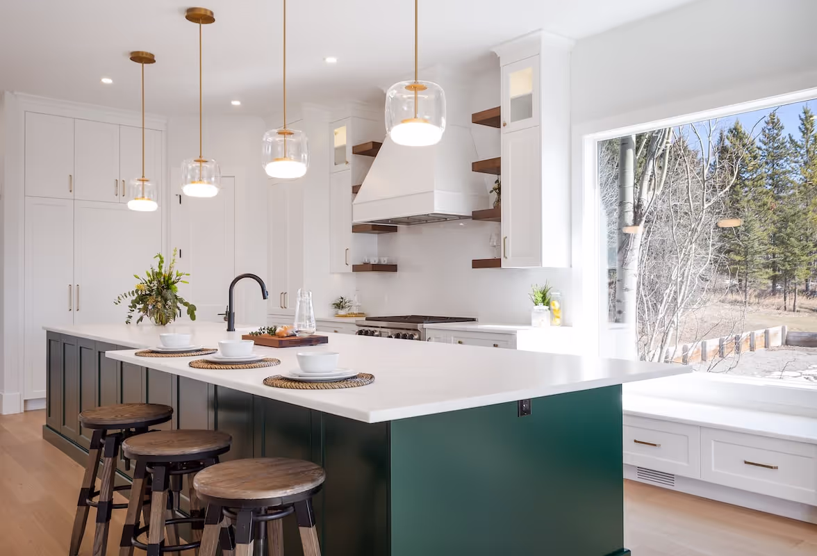 Kitchen featuring custom green island with built-in shelving, white perimeter cabinets, and luxury millwork details. Cabinetry by Marvel Cabinetry.