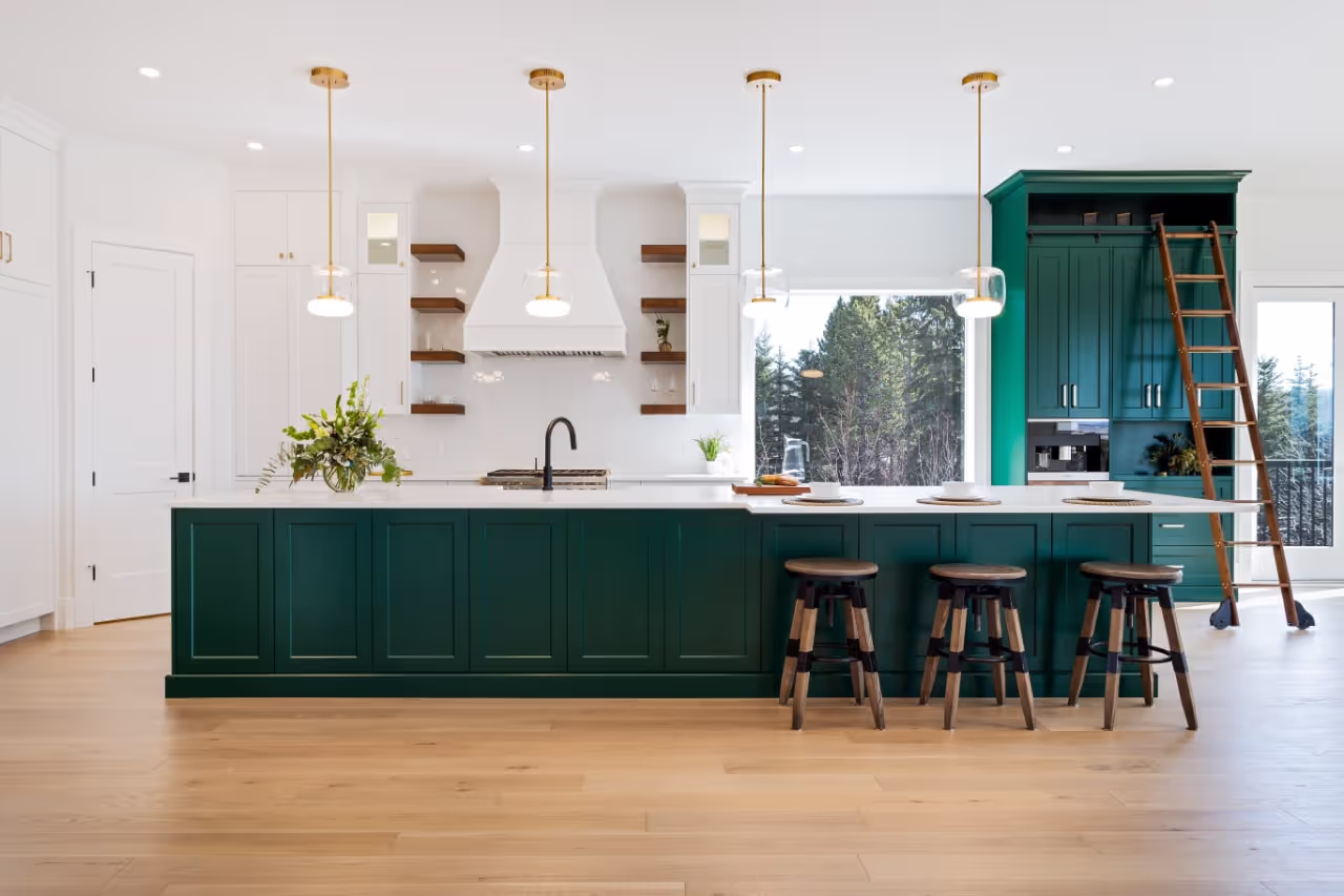 Modern kitchen with custom green island cabinetry, gold hardware, pendant lighting, and integrated storage. Cabinetry by Marvel Cabinetry.