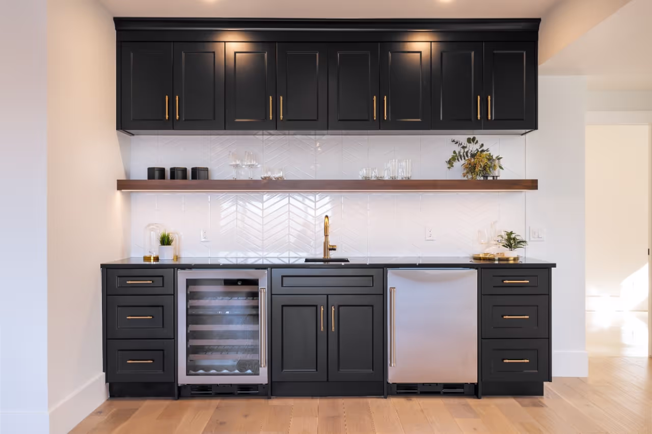 Black custom bar cabinetry with glass uppers, wine storage, beverage fridge, and elegant display shelving. Cabinetry by Marvel Cabinetry.