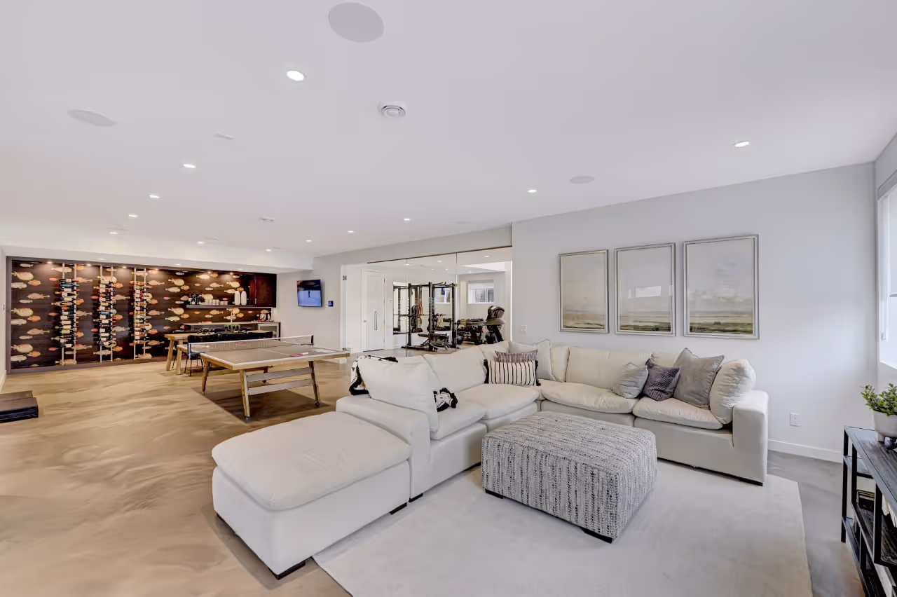 Cozy basement living room with custom shelving, sectional seating, and integrated entertainment cabinetry. Cabinetry by Marvel Cabinetry.