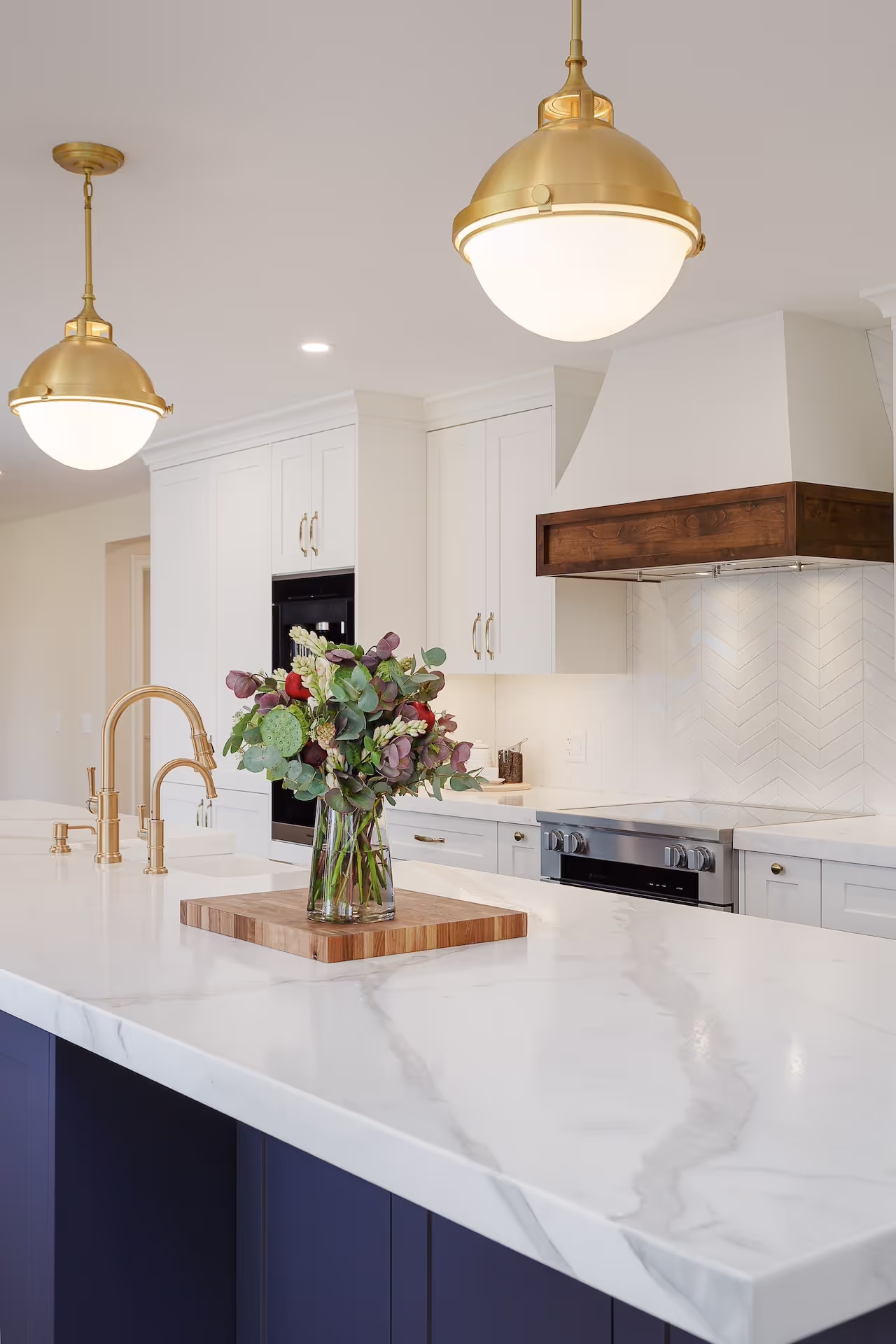Close-up of navy kitchen island with quartz countertop, gold fixtures, and high-end custom millwork. Cabinetry by Marvel Cabinetry.
