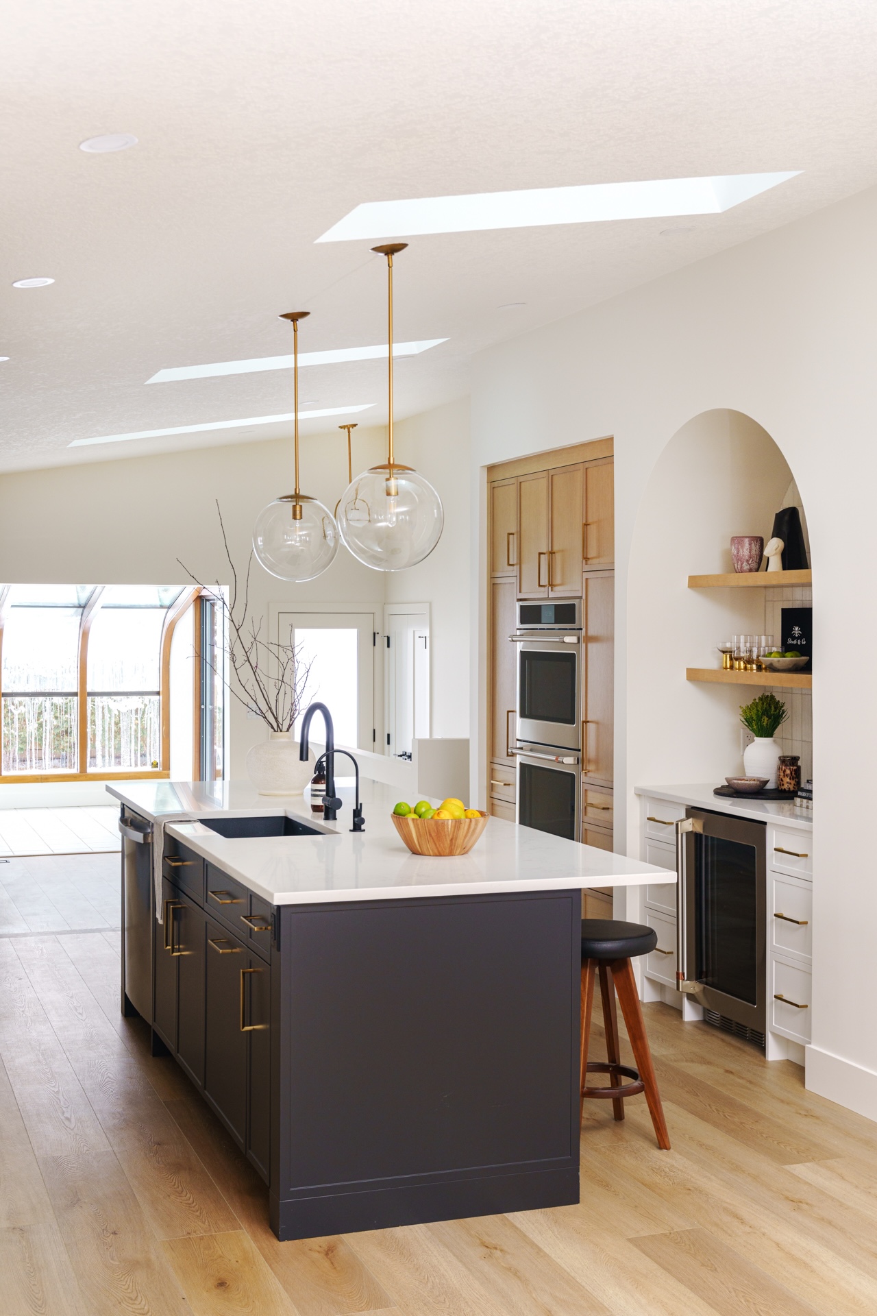 Modern kitchen island with stone countertop, dark base cabinets, and open-concept dining area. Cabinetry by Marvel Cabinetry.