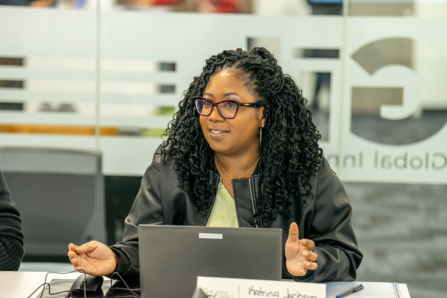 Woman with glasses sitting at a computer and making a comment during the presentation