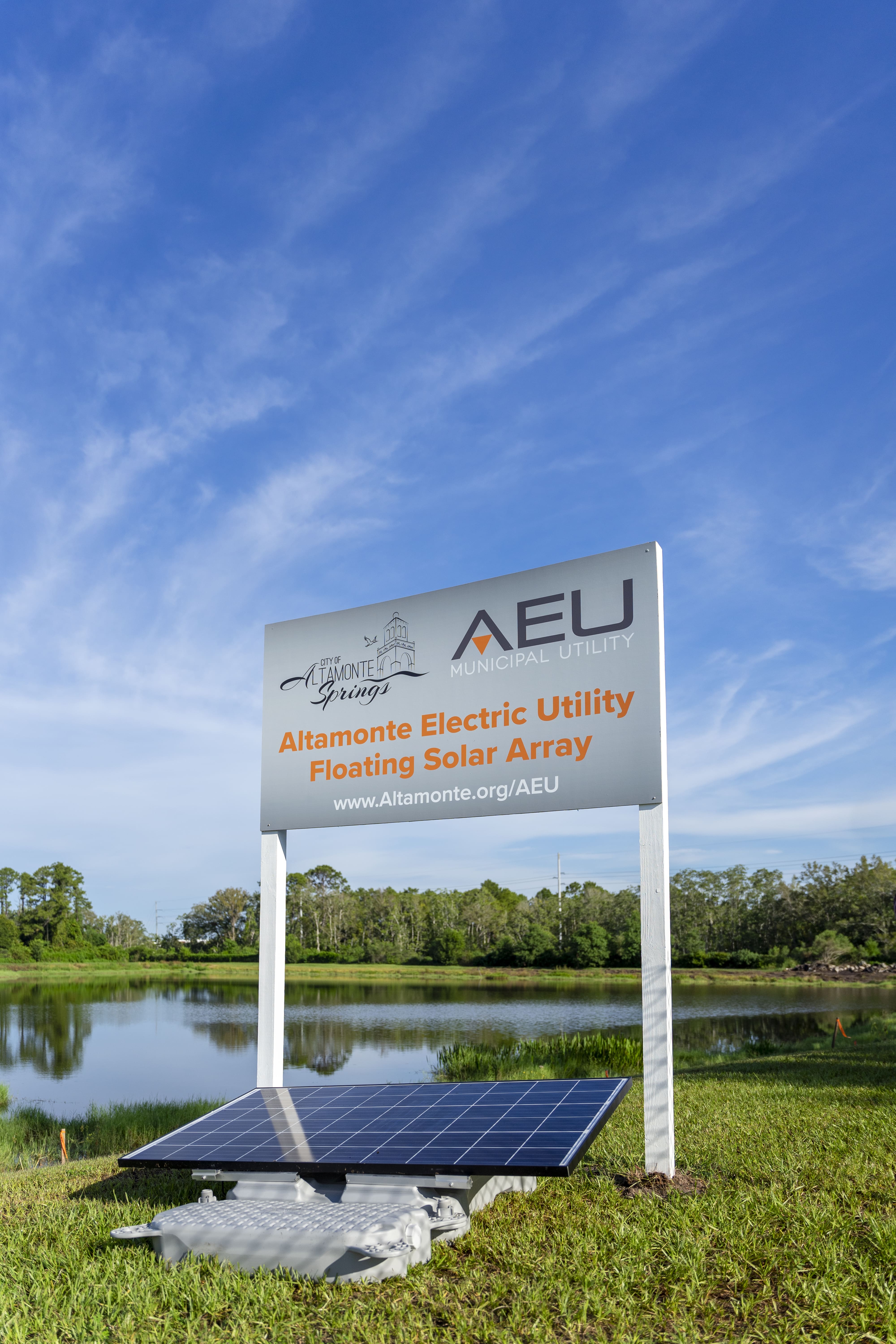 AEU project sign next to the pond with solar panels