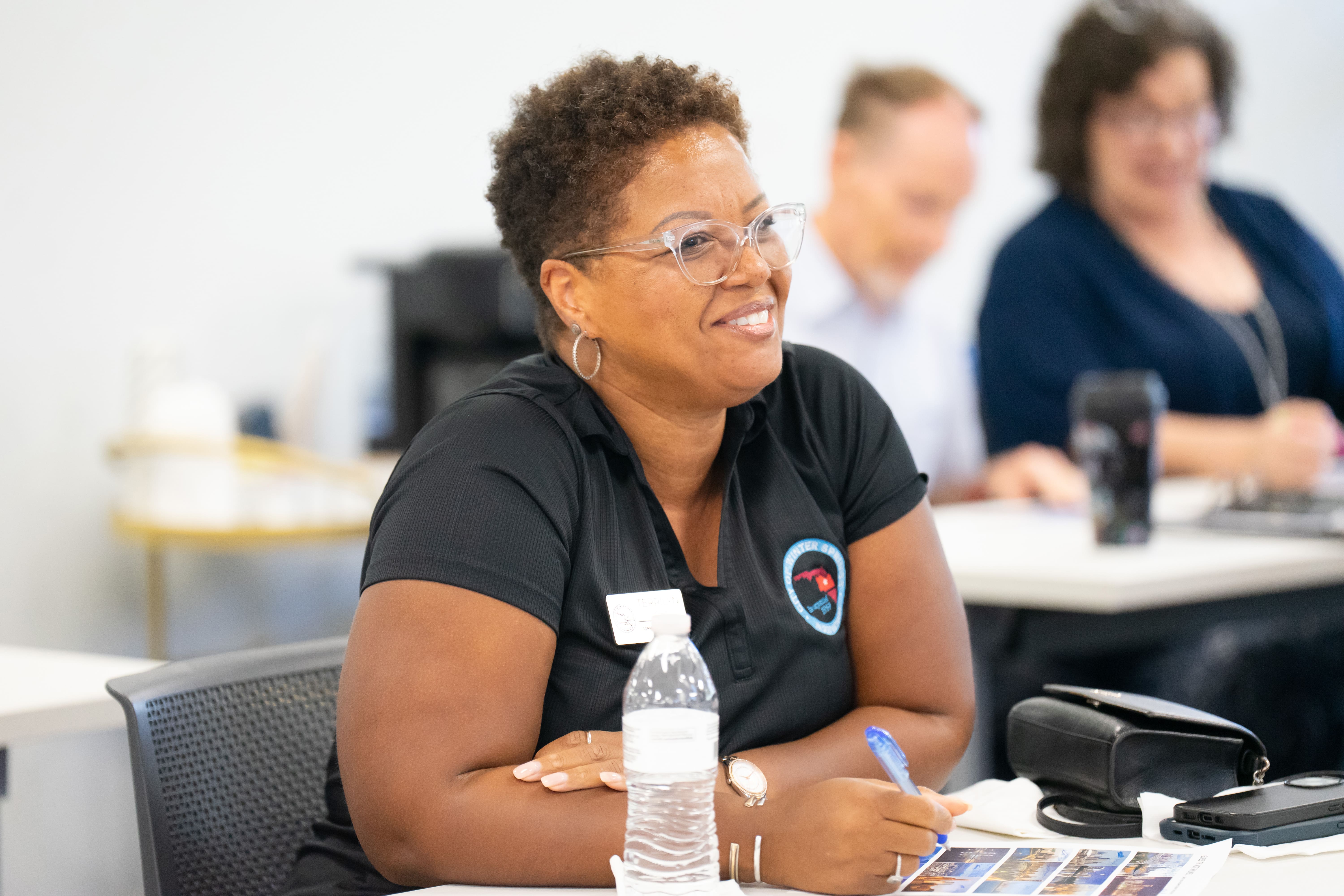 Smiling women sitting at a table listening to a lecture