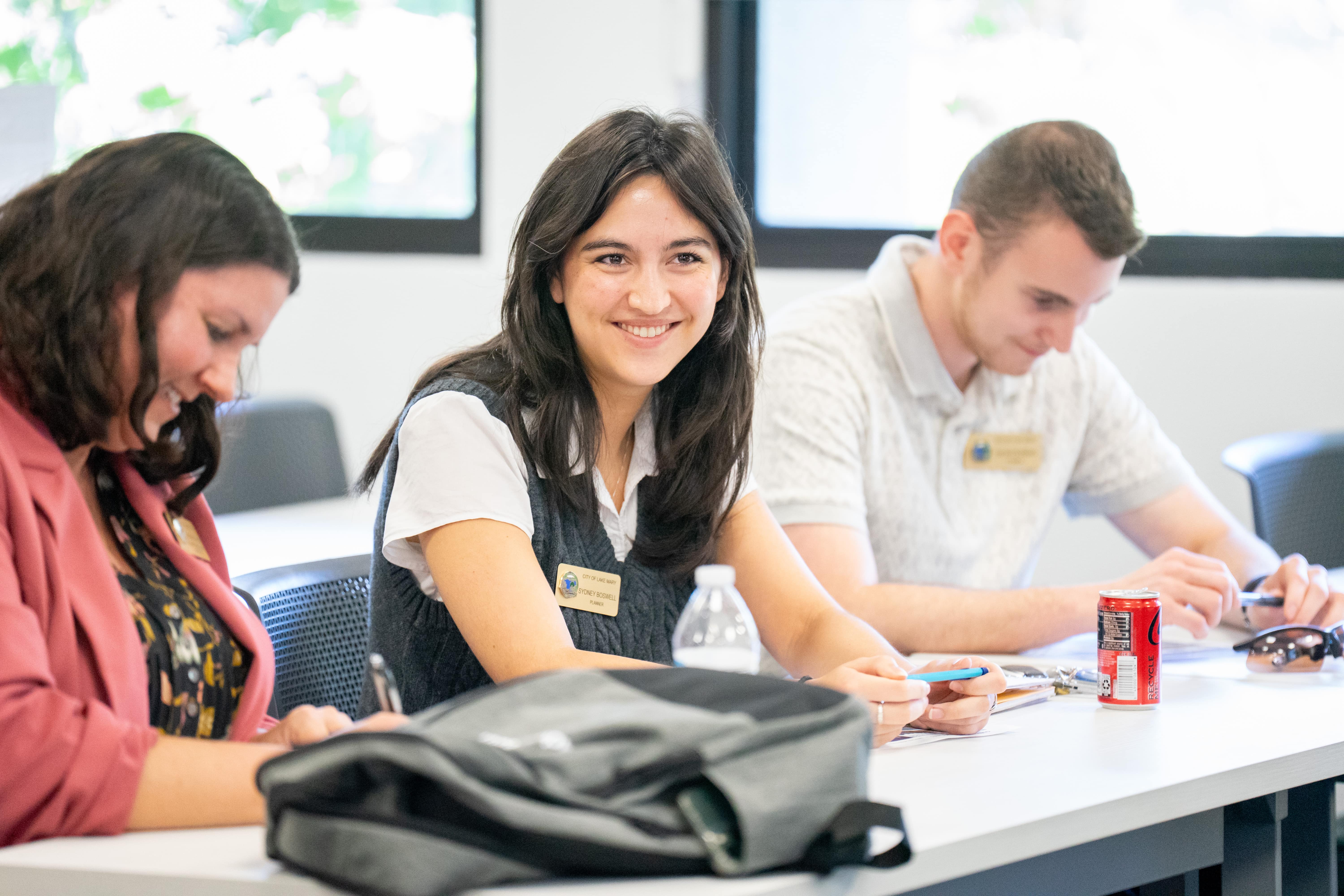 Smiling women sitting at a table listening to a lecture
