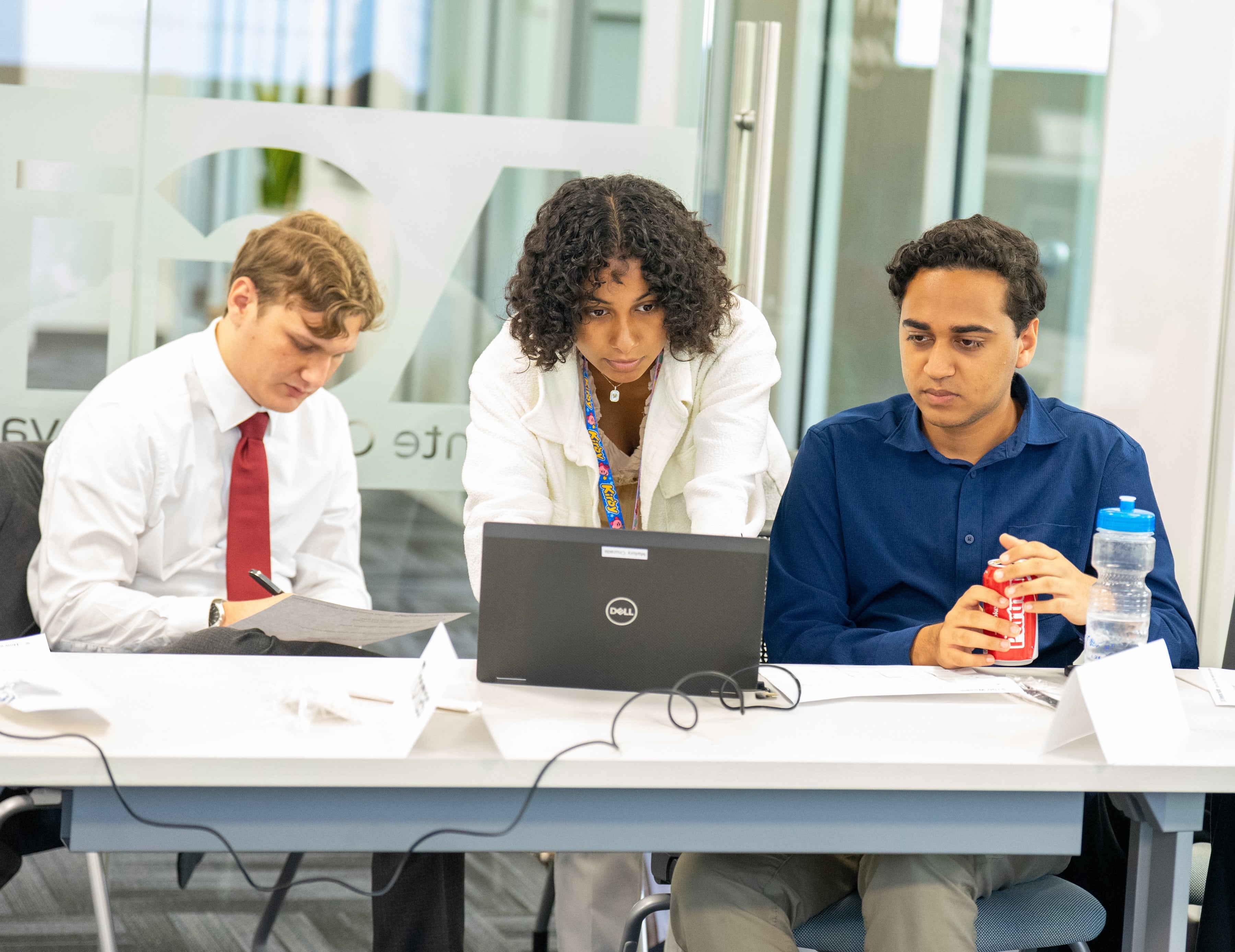 Students sitting at a table and looking together at a laptop