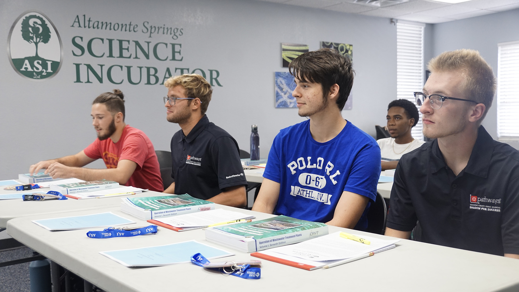 Students sitting at a table listen intently to a presentation