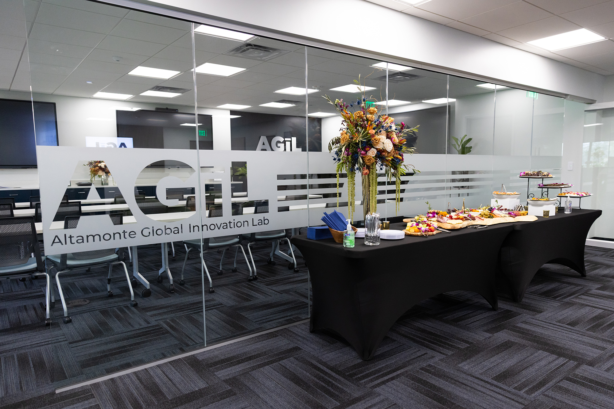 Buffet table with flowers and food in front of a glass wall
