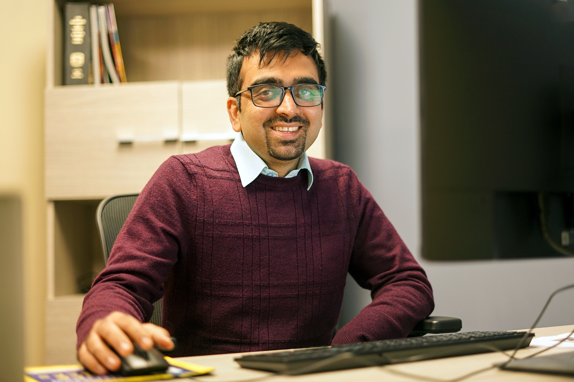 Student intern sitting at a computer smiling at the camera