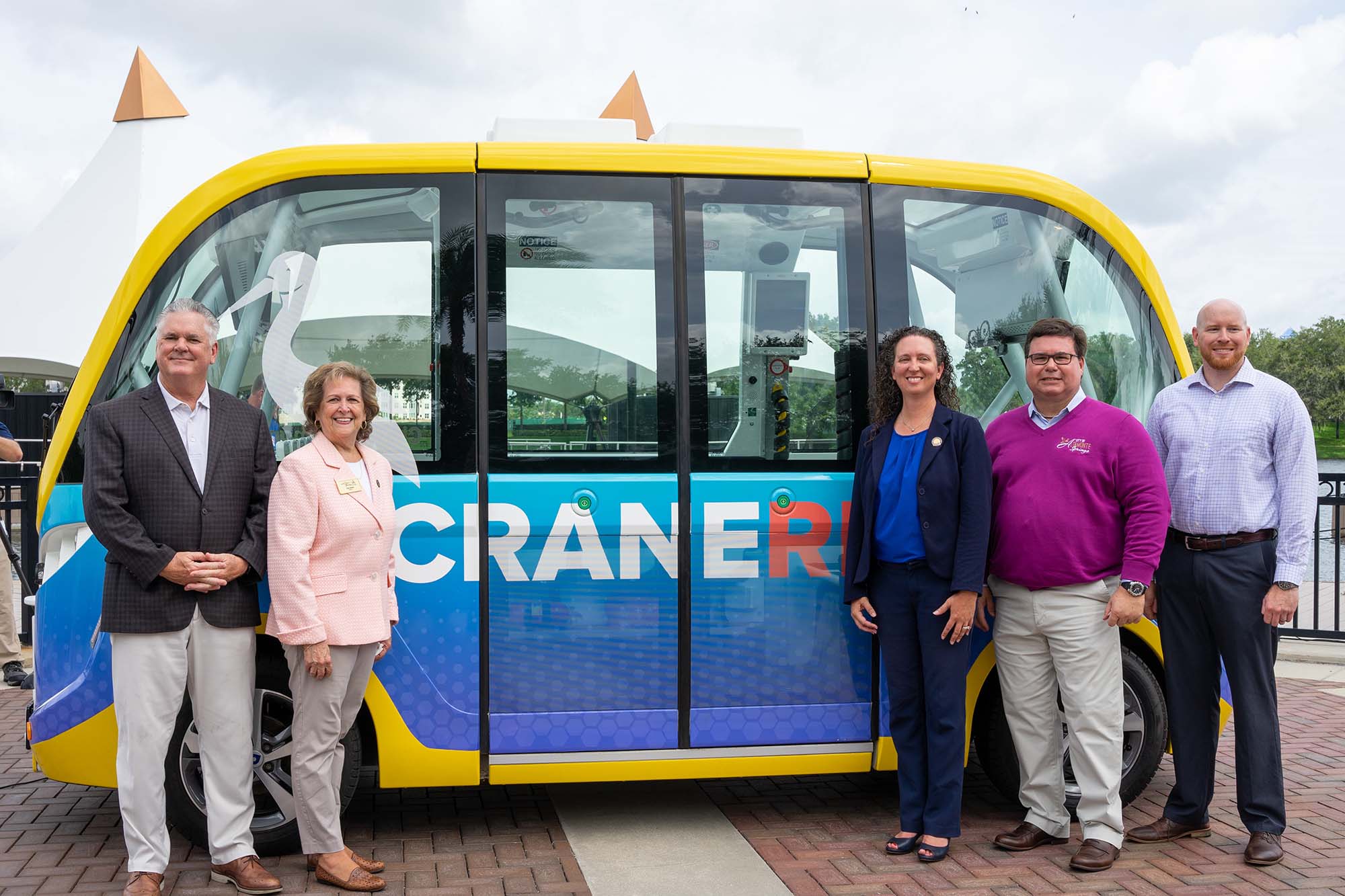 Project stakeholders pose for the camera in front of the CraneRIDES shuttle