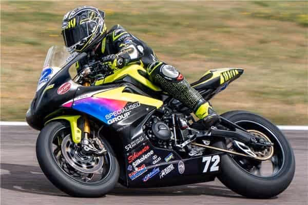 Motorcycle racer leaning into turn on yellow and black sports bike