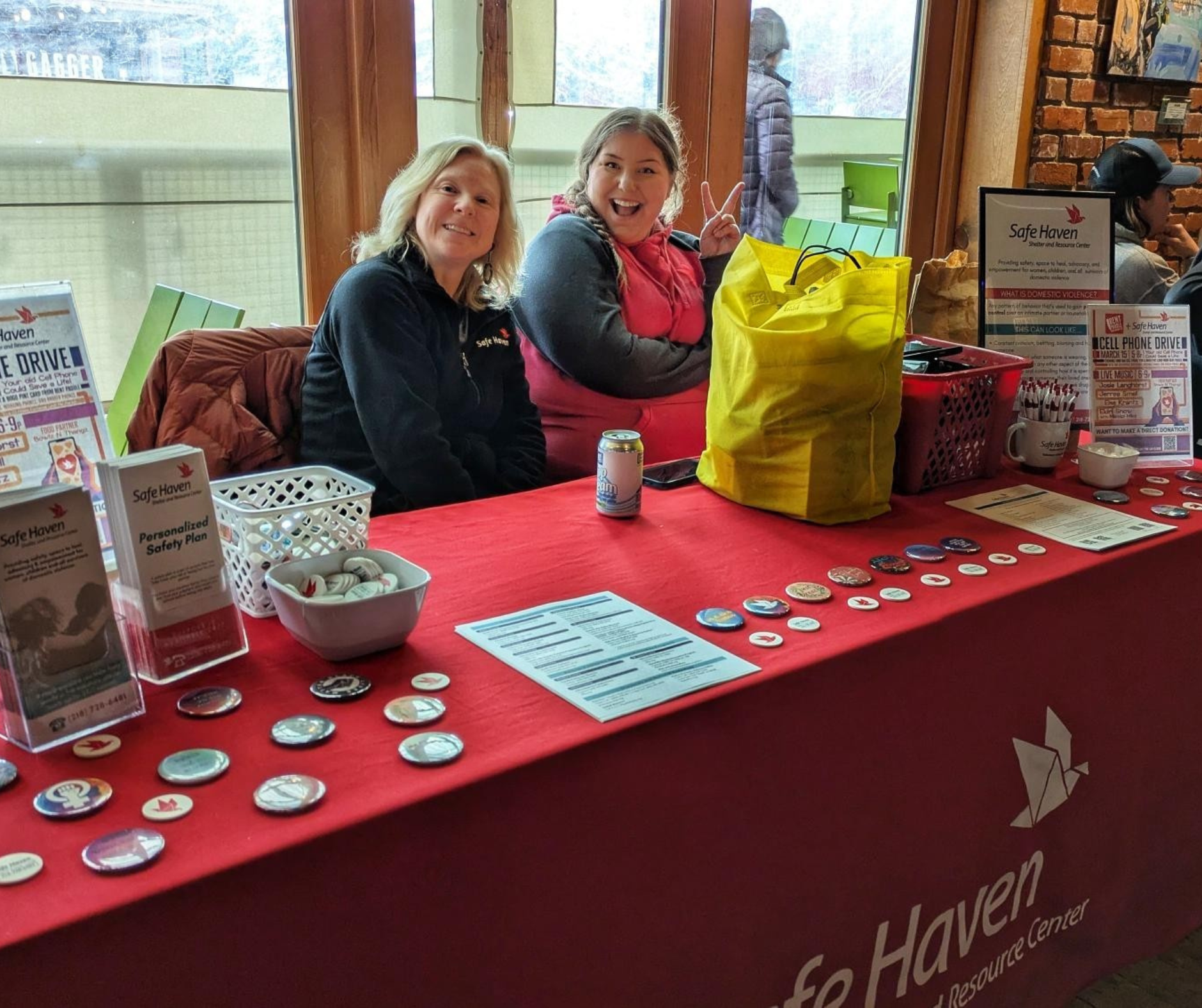 Two women at a resource table at an event handing out crisis chips and Safe Haven resources.