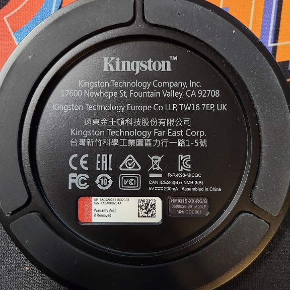A photo of the underside of a HyperX microphone base stand, showing the SN sticker (bottom left) and the part number sticker (bottom right).