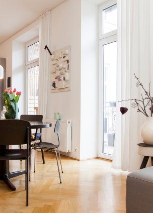 Ansicht eines hellen Zimmers mit Parkettboden und dunklen Holzmöbeln.