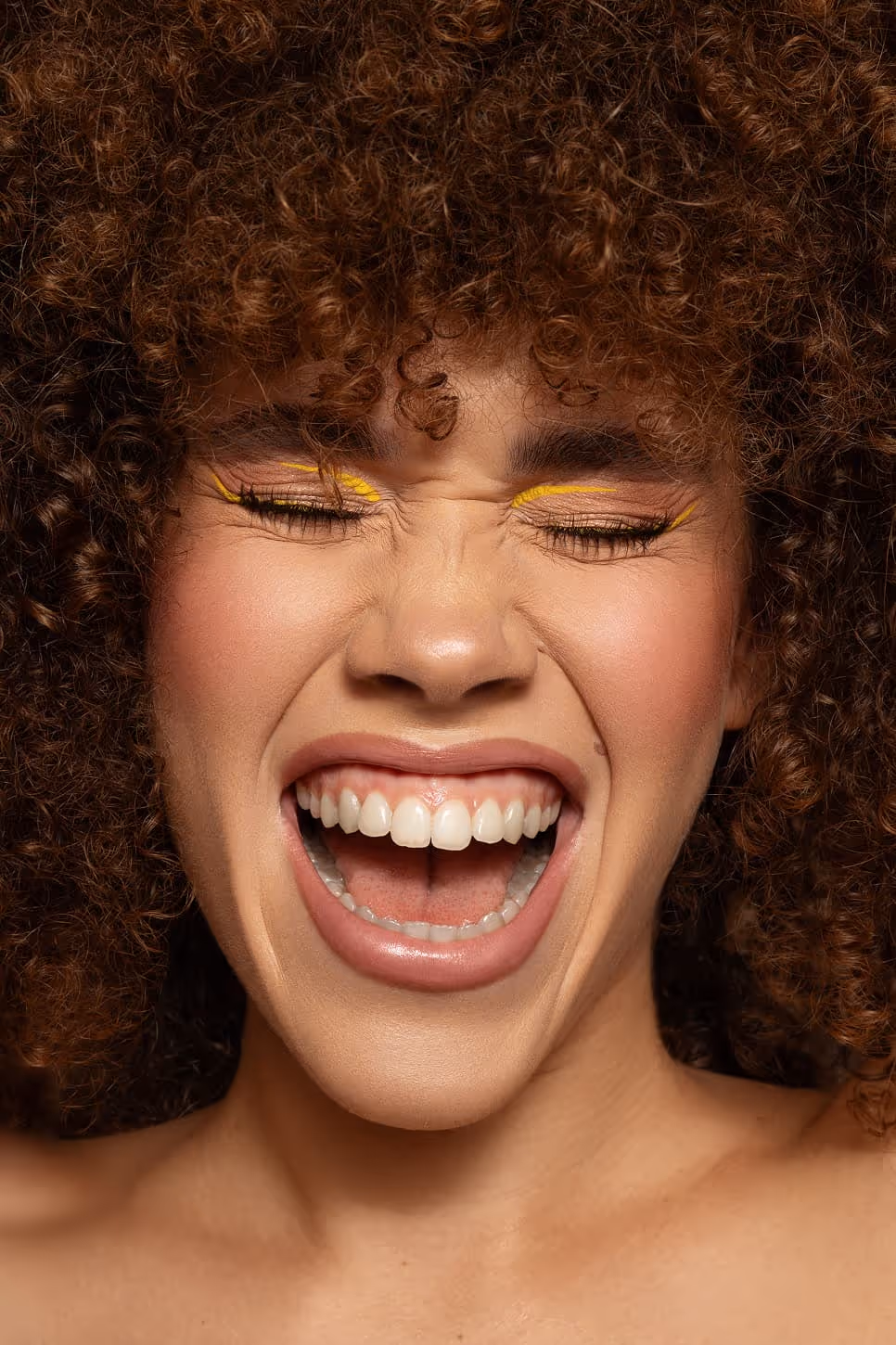 Veseli beauty portret sa afro kovrdžama i žutim eyelinerom – artistički makeup look koji naglašava energiju i prirodnu lepotu, rad profesionalnog šminkera Sare Ivanović iz Pančeva.