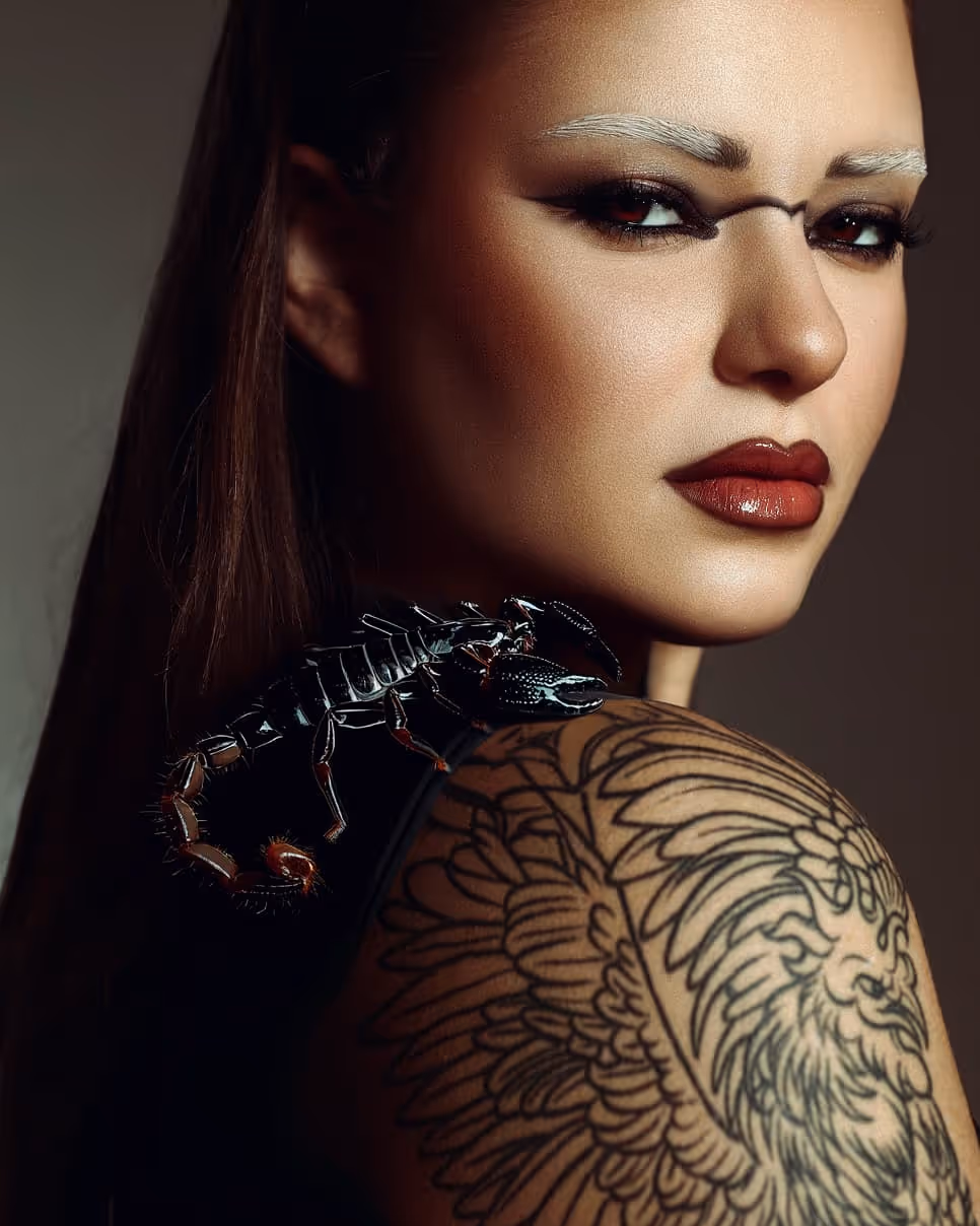 Artistički makeup sa crvenim ružem, izraženim obrvama i eyelinerom – modna fotografija sa skorpijom na ramenu i tetovažom, rad profesionalnog šminkera Sare Ivanović iz Pančeva.