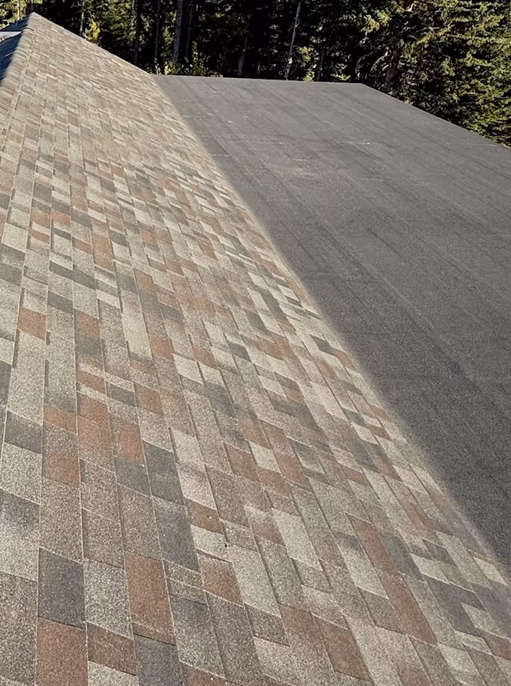 Side-by-side view of a newly installed multi-colored shingle roof next to an old black roofing surface.
