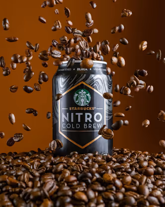 Starbucks Nitro Cold Brew can surrounded by flying coffee beans, beverage product photography by Photos by Lars.