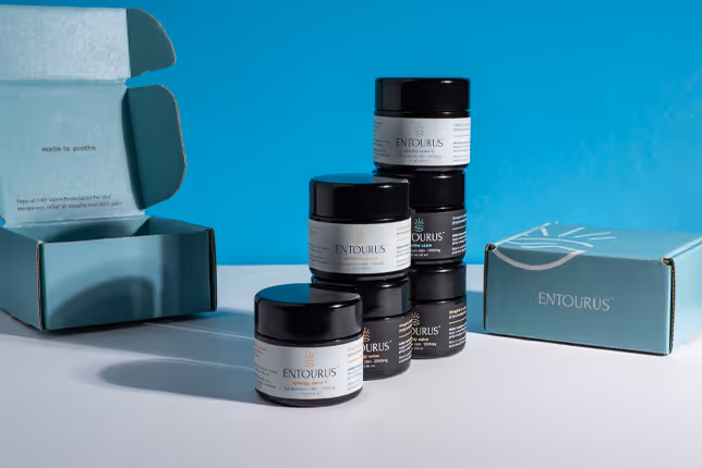 Entourus CBD Salve jars and teal packaging arranged on light blue set, product photography by Photos by Lars.