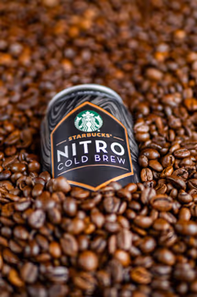 Starbucks Nitro Cold Brew can label peeking through a bed of coffee beans, product photography by Photos by Lars.