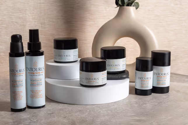 Entourus skincare collection arranged on white pedestals beside a ceramic vase, product photography by Photos by Lars.