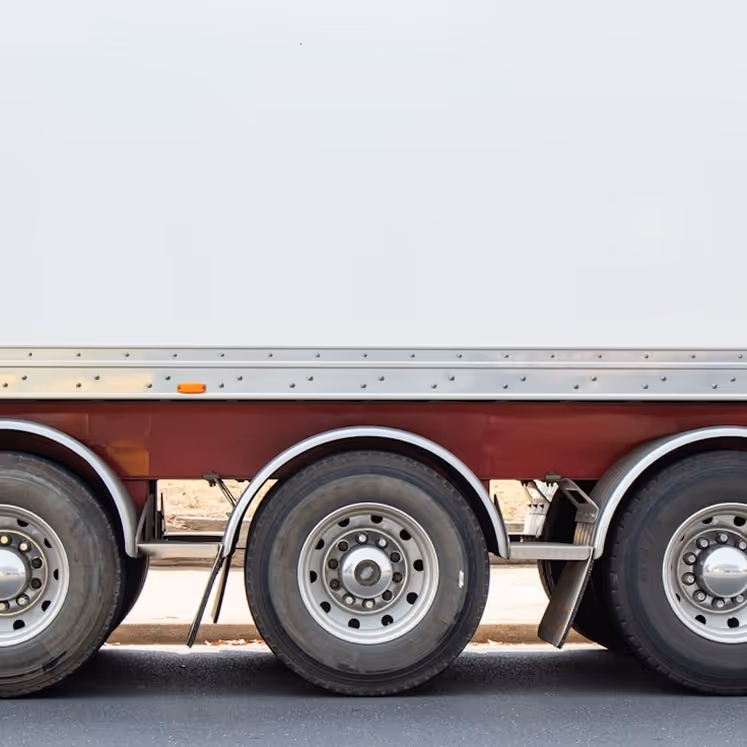 Side view of three wheels on a large trailer truck with white and maroon body.