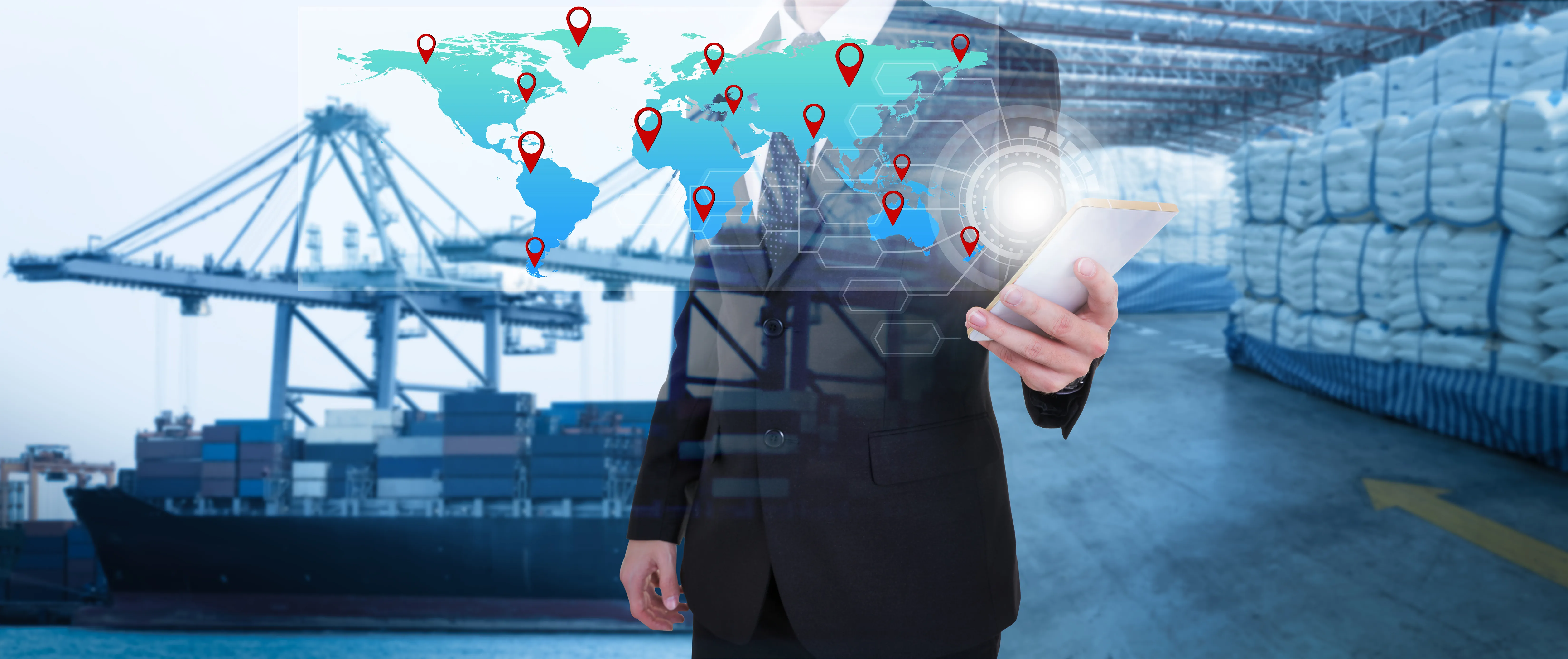 Businessman in suit using tablet with digital world map and location markers overlay in a shipping port and warehouse background.