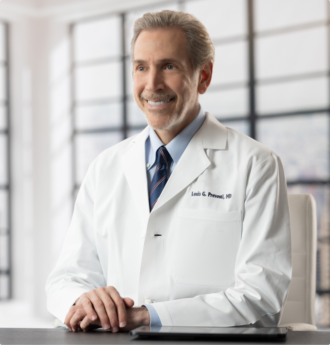 Dr. Louis Prevosti sitting at a desk during a consultation with a patient