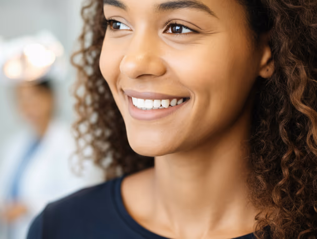 Close-up of a smiling young woman with curly hair looking to the side.