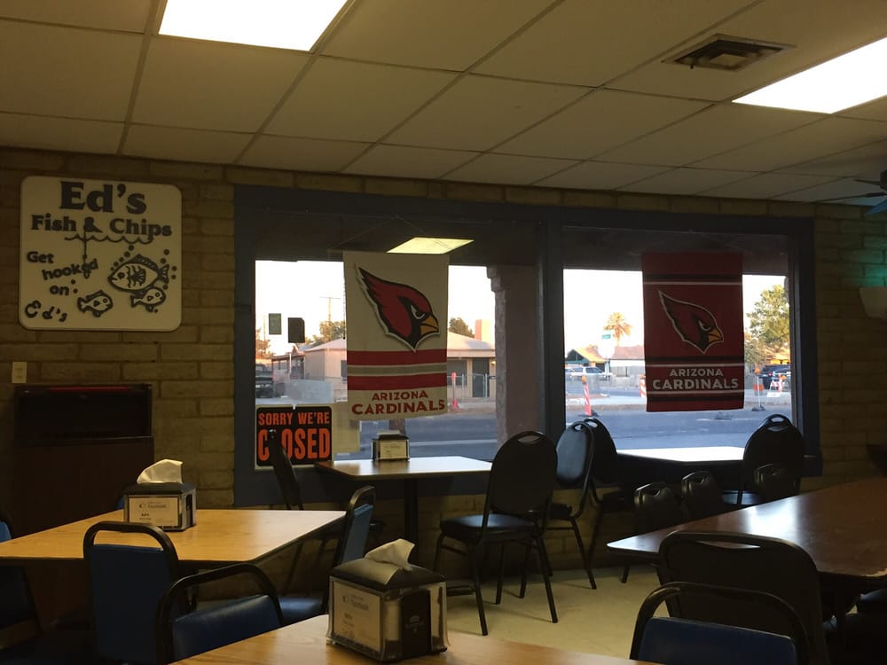 Ed's Fish & Chips interior featuring tables and chairs arranged near a large window, allowing natural light to fill the space.