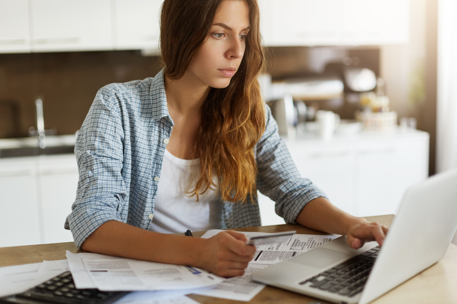 Woman reviewing paperwork and using a laptop