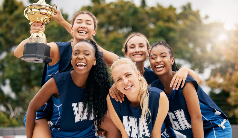 Girls sports team celebrating with trophy