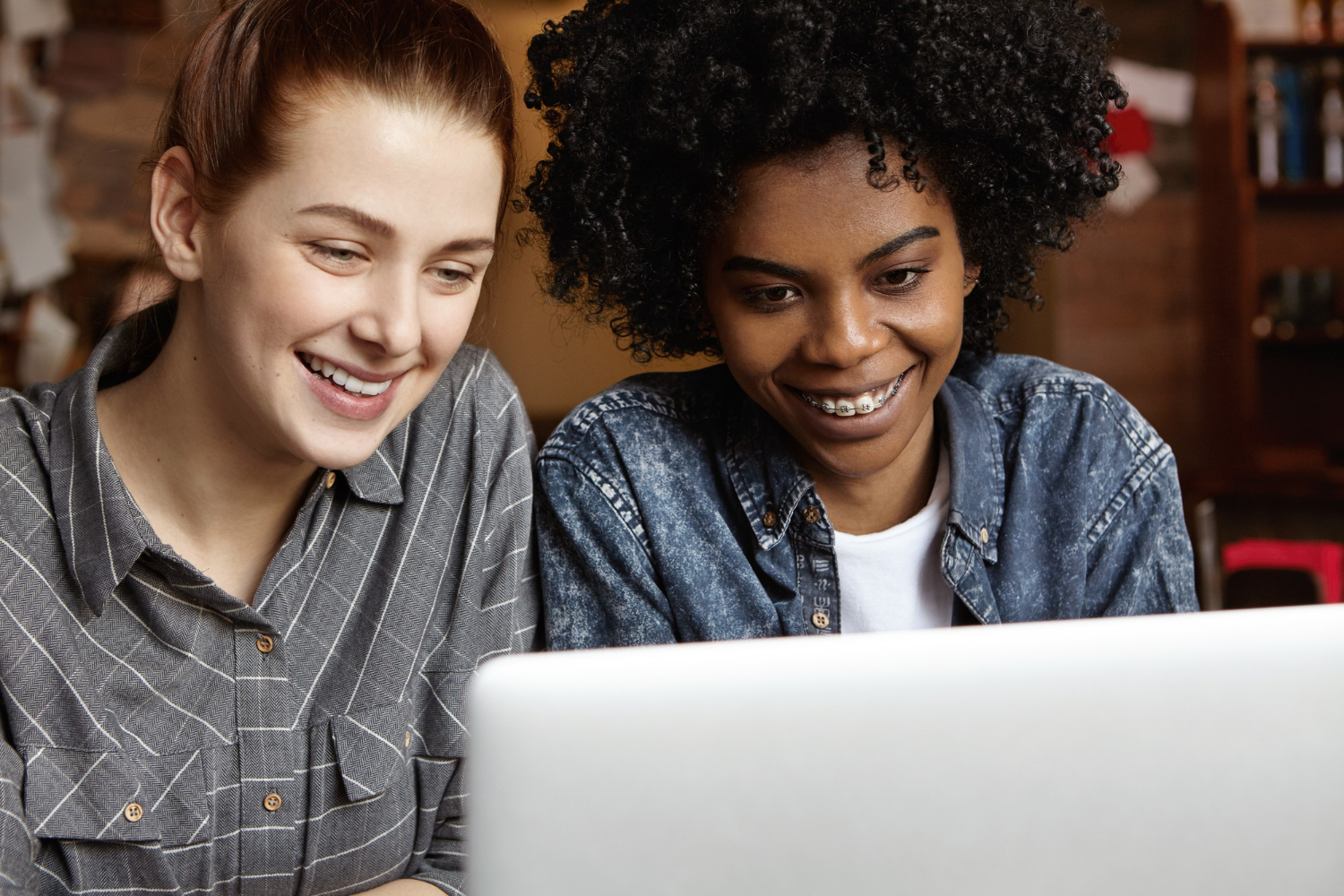 Two women smiling while working on laptop