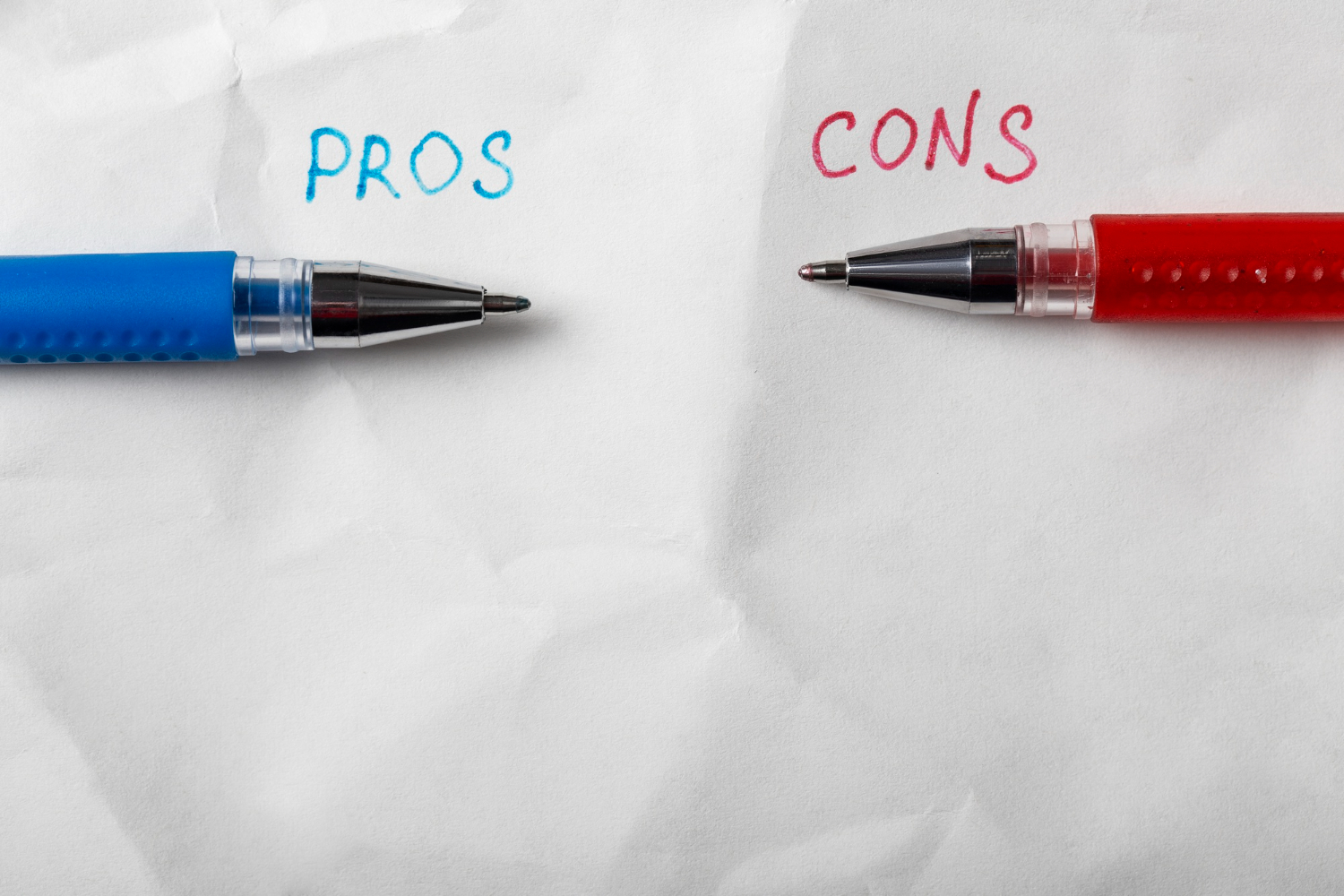 Pros and cons written between two pens