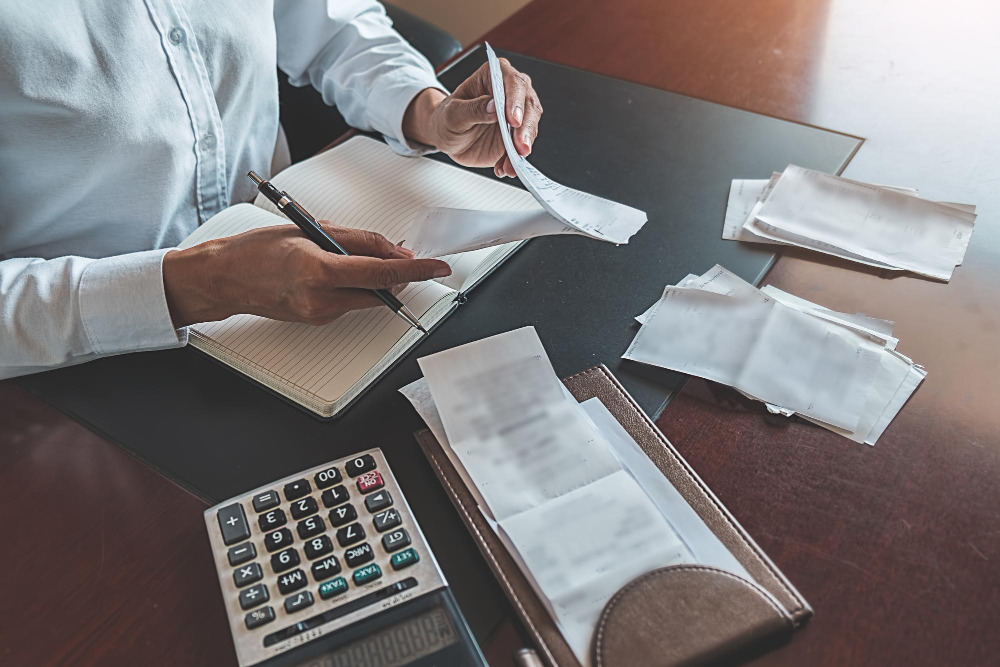 Business owner reviewing expenses and receipts with calculator for tax preparation