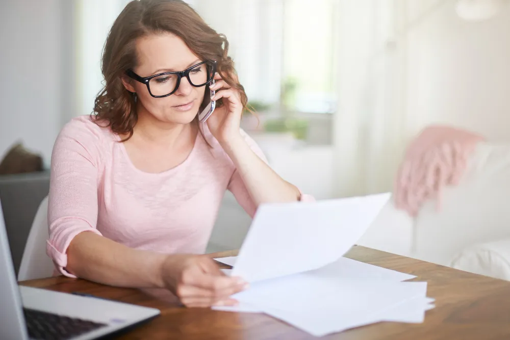 Woman business owner reviewing IRS letter and calling for help with taxes.