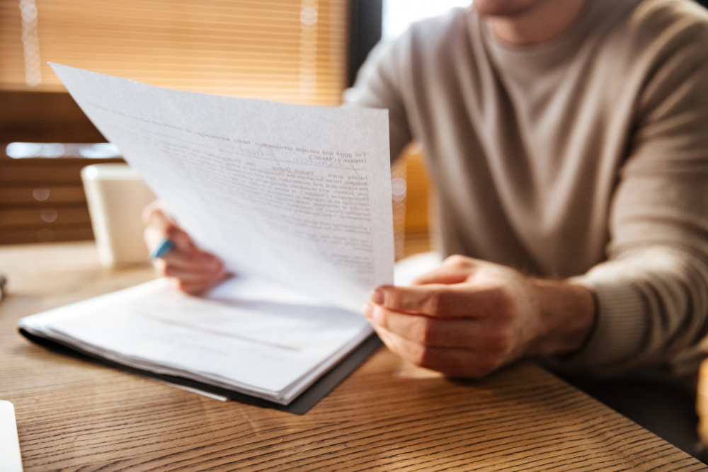 Man reviewing IRS notice letter at home with financial documents on desk.