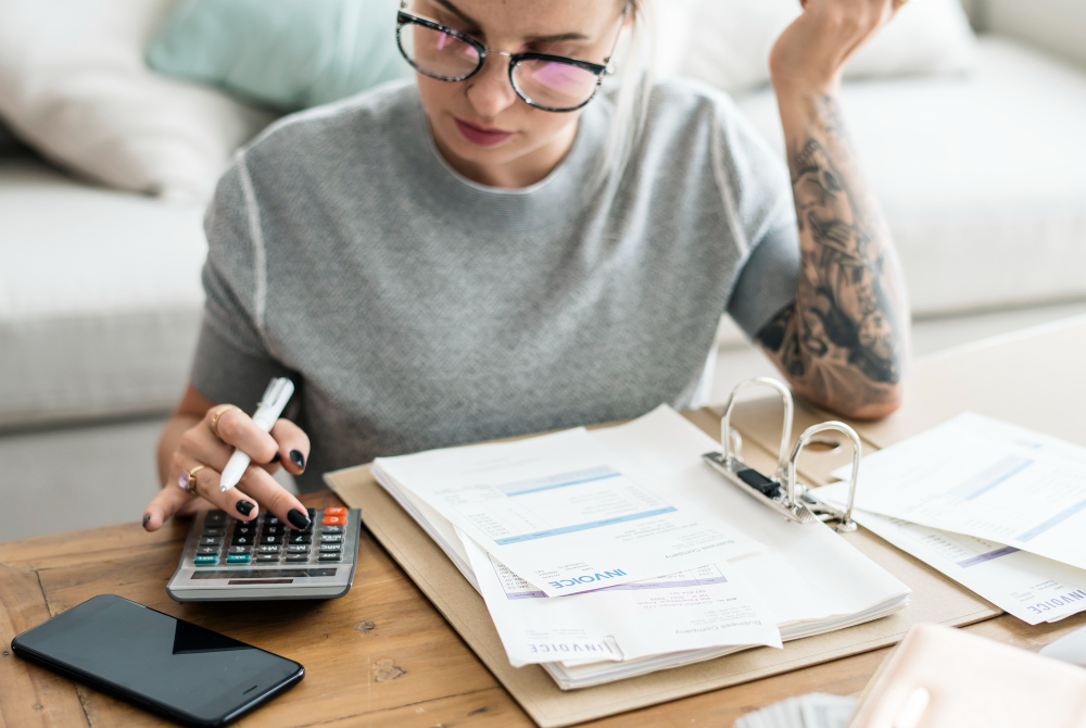 Woman calculating bills and reviewing tax paperwork at home.