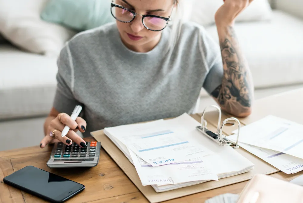 Woman calculating bills and reviewing tax paperwork at home.