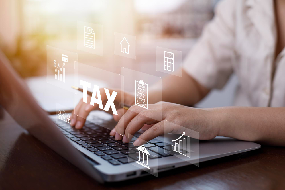 Person using a laptop to prepare tax documents online with digital tax and financial planning icons displayed over the workspace, representing electronic tax filing and tax preparation services.