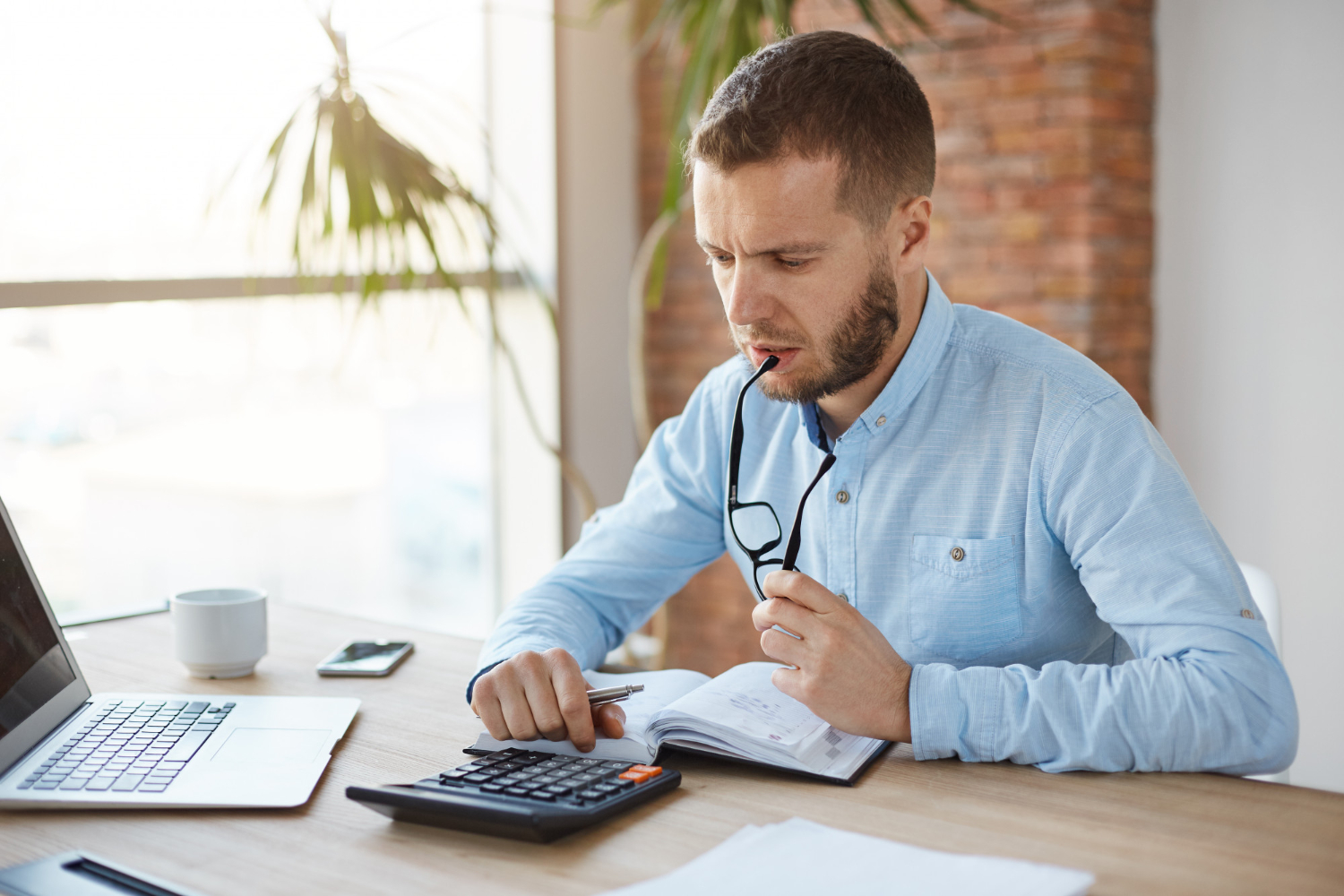 Man reviewing finances with calculator and laptop in office