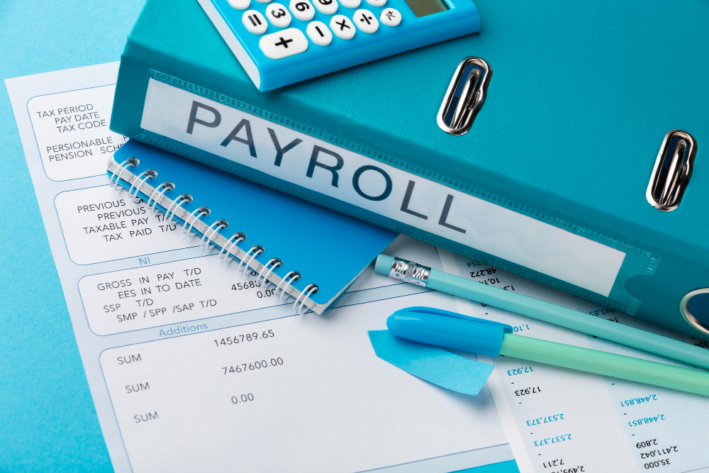 Payroll folder, calculator, and payroll documents on office desk