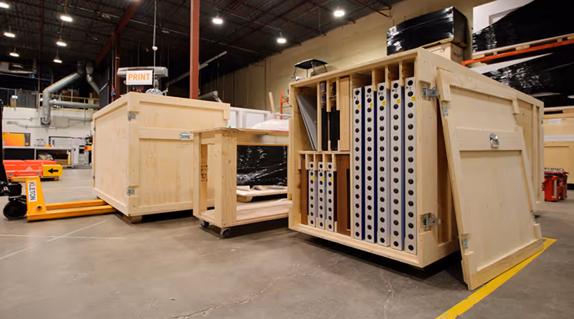 Large wooden crates and a pallet jack inside a warehouse with organized storage compartments visible in one crate.