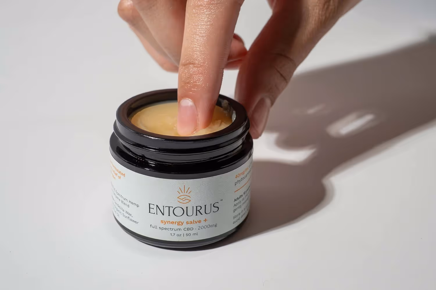 Finger dipping into an Entourus jar on white background with shadow, product photography by Photos by Lars.