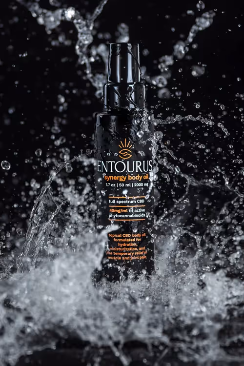 Entourus bottle bursting through a water splash on black background, product photography by Photos by Lars.