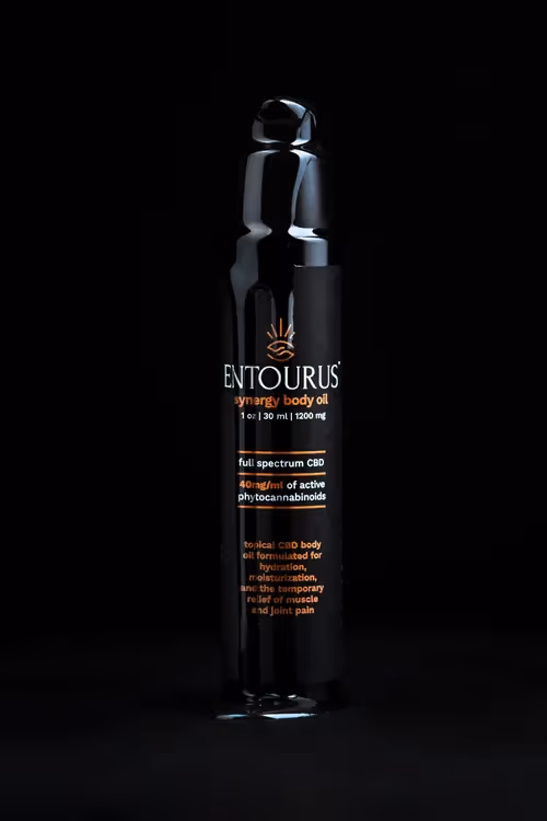 Tall Entourus pump bottle lit on black background with oil flowing down, product photography by Photos by Lars.