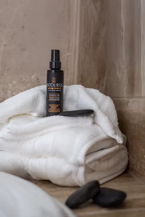 Entourus spray bottle standing beside rolled white towels, product photography by Photos by Lars.